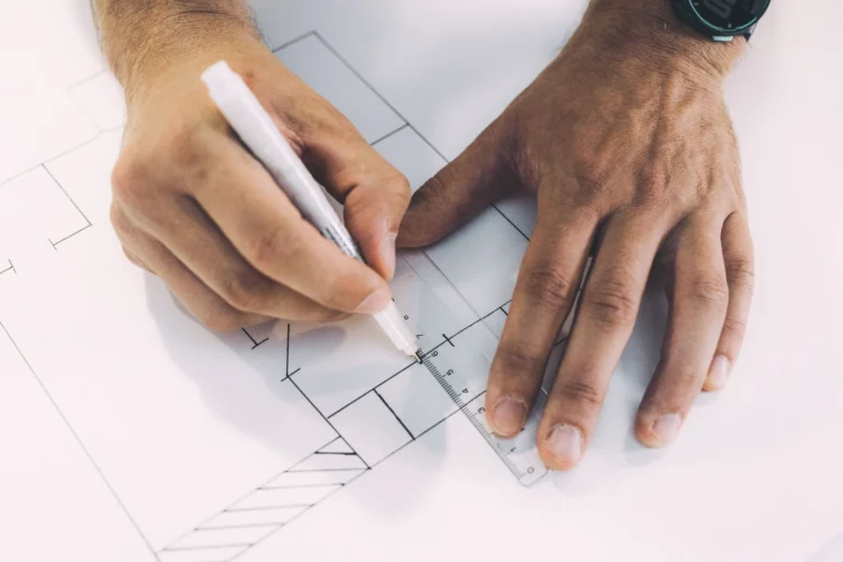 Manos dibujando un croquis arquitectónico con regla y lápiz