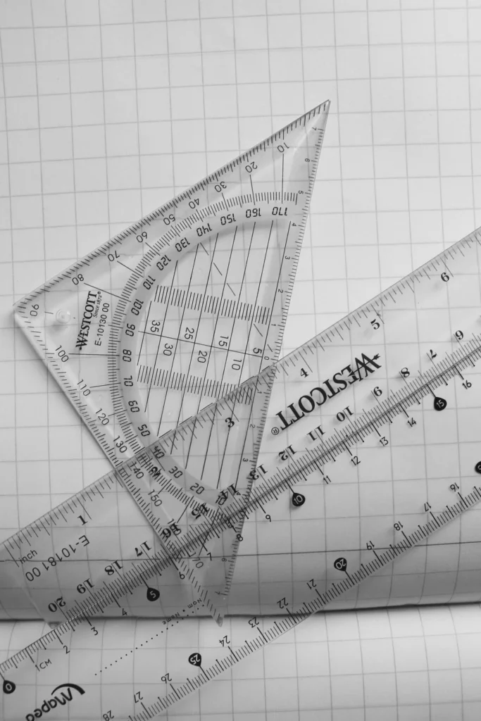 Reglas transparentes y transportador sobre papel milimétrico en matemáticas para arquitectura